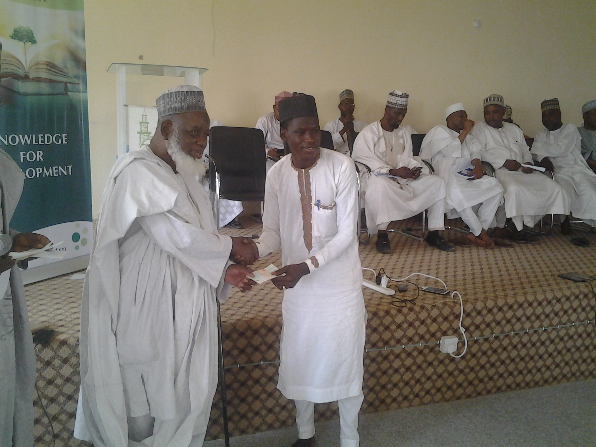 Alhaji Ado Muhammad presenting cheque to beneficiary