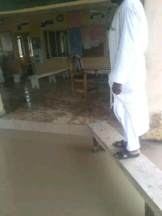 Official standing on a bench to cross the flooded entrance at Walawa PHC